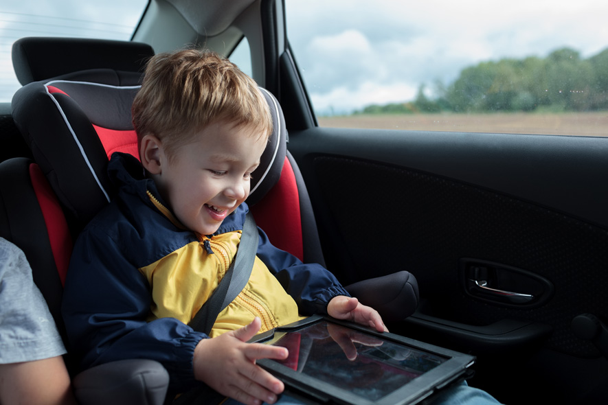 Kid in car playing with tablet