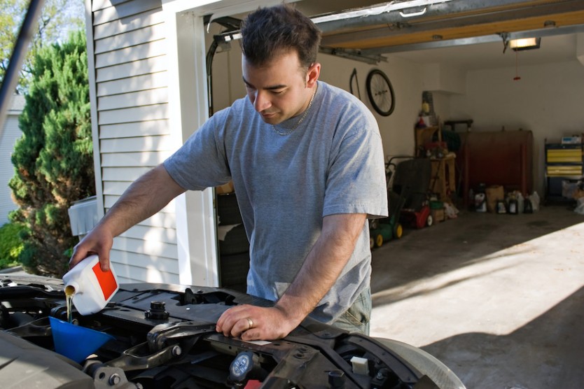 Man Changing the Oil in front of his garage